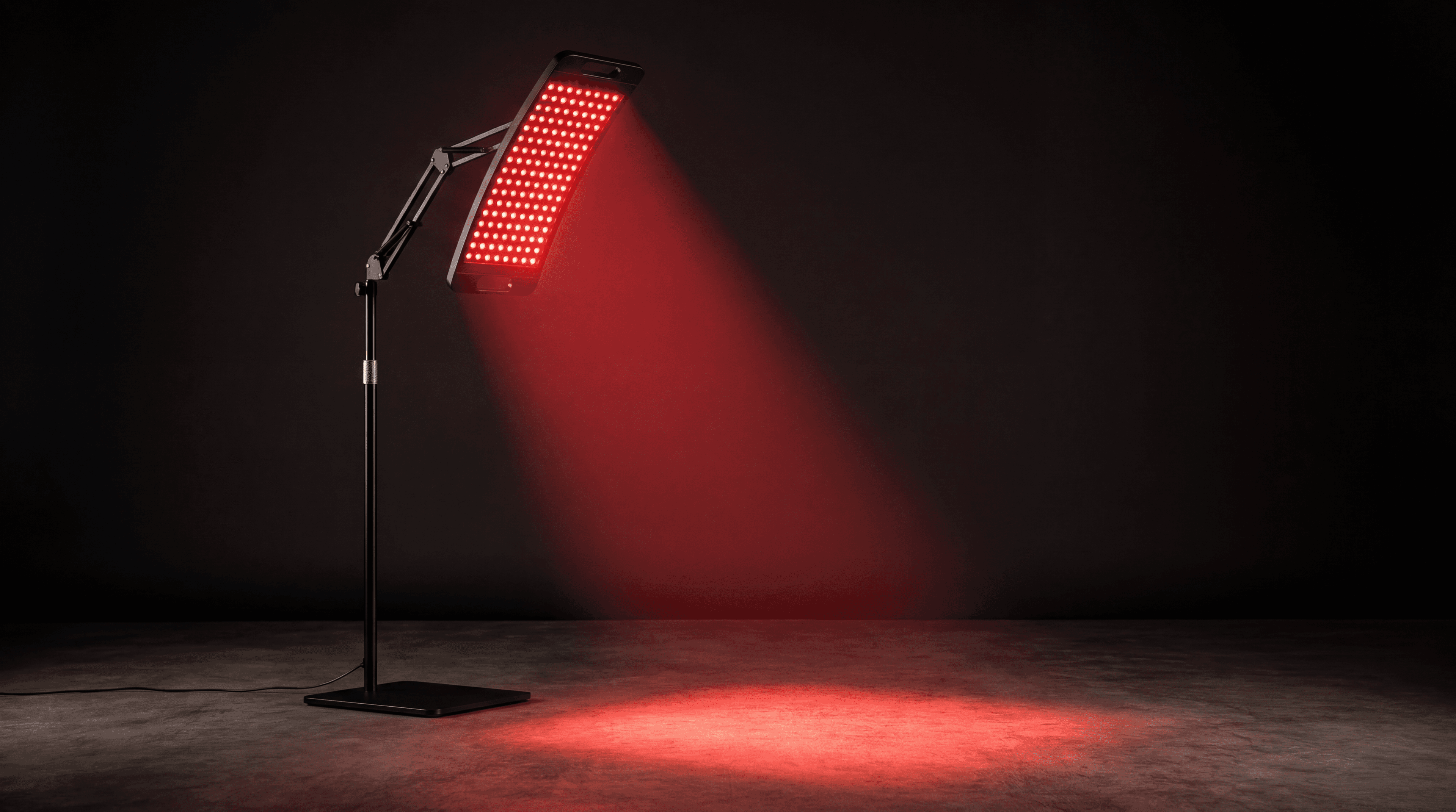 The Lumora Halo recovery lamp glowing red on its stand in a dark studio